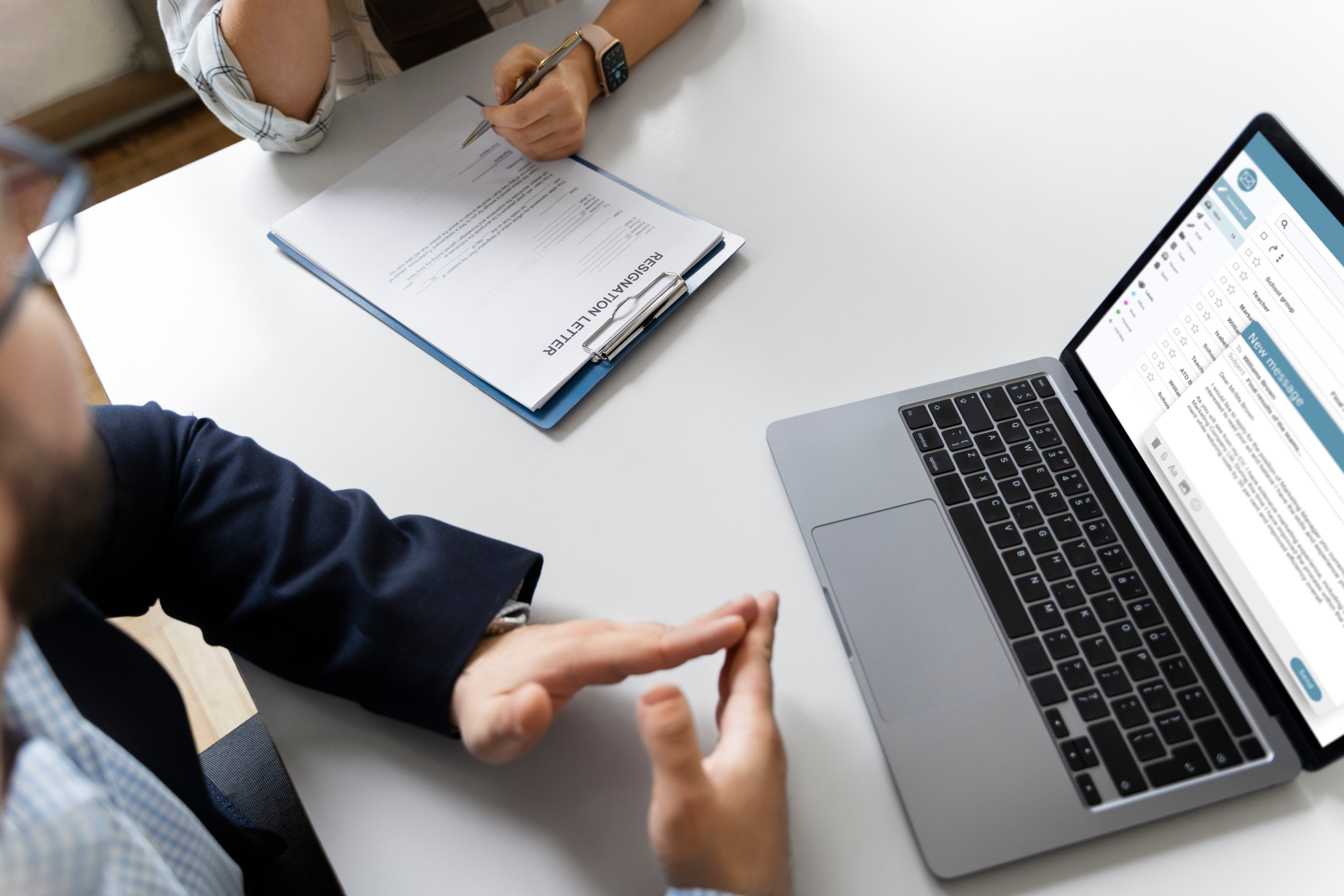 Manos sobre escritorio, portátil y documentos.