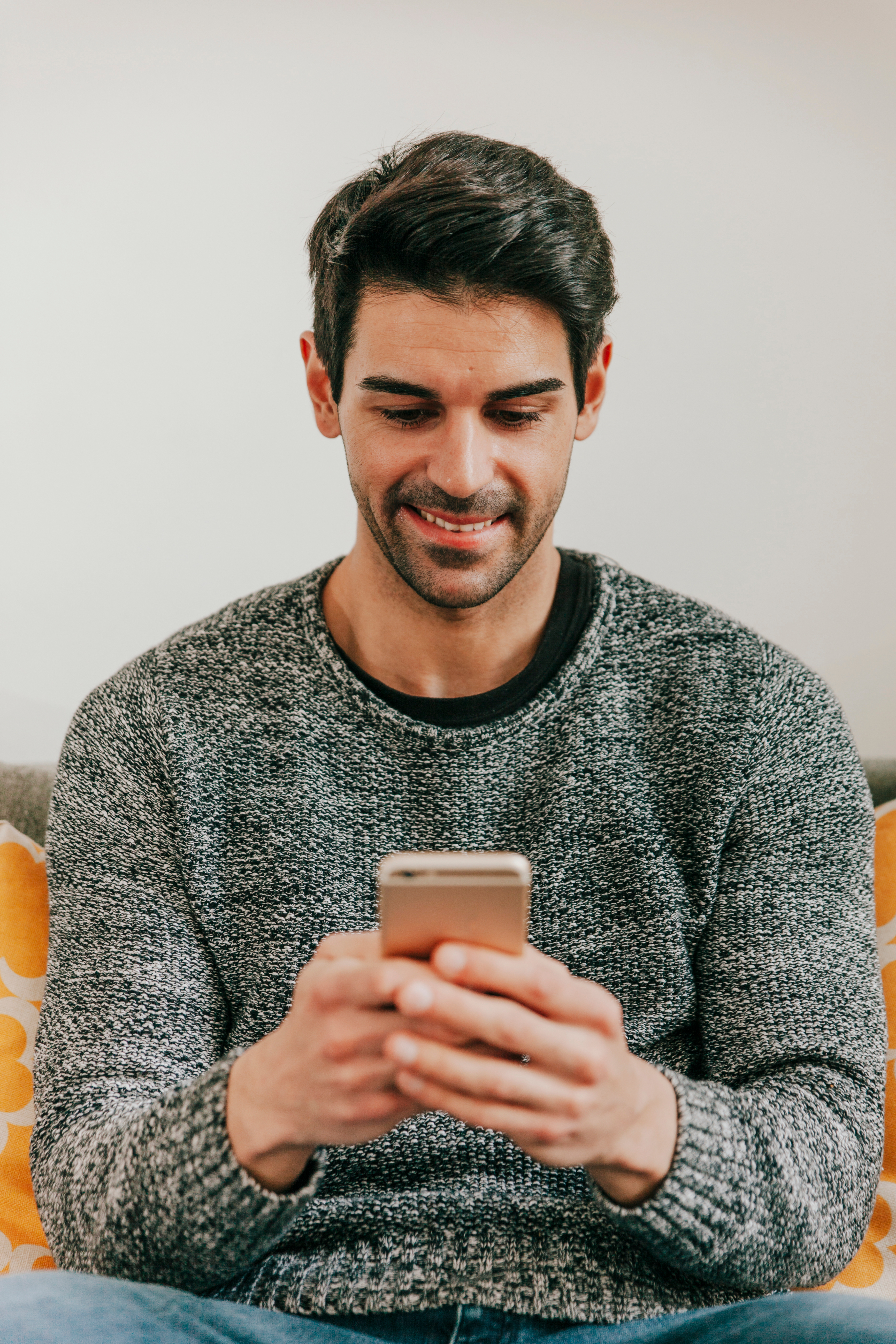 Hombre sonriendo mientras usa su celular.