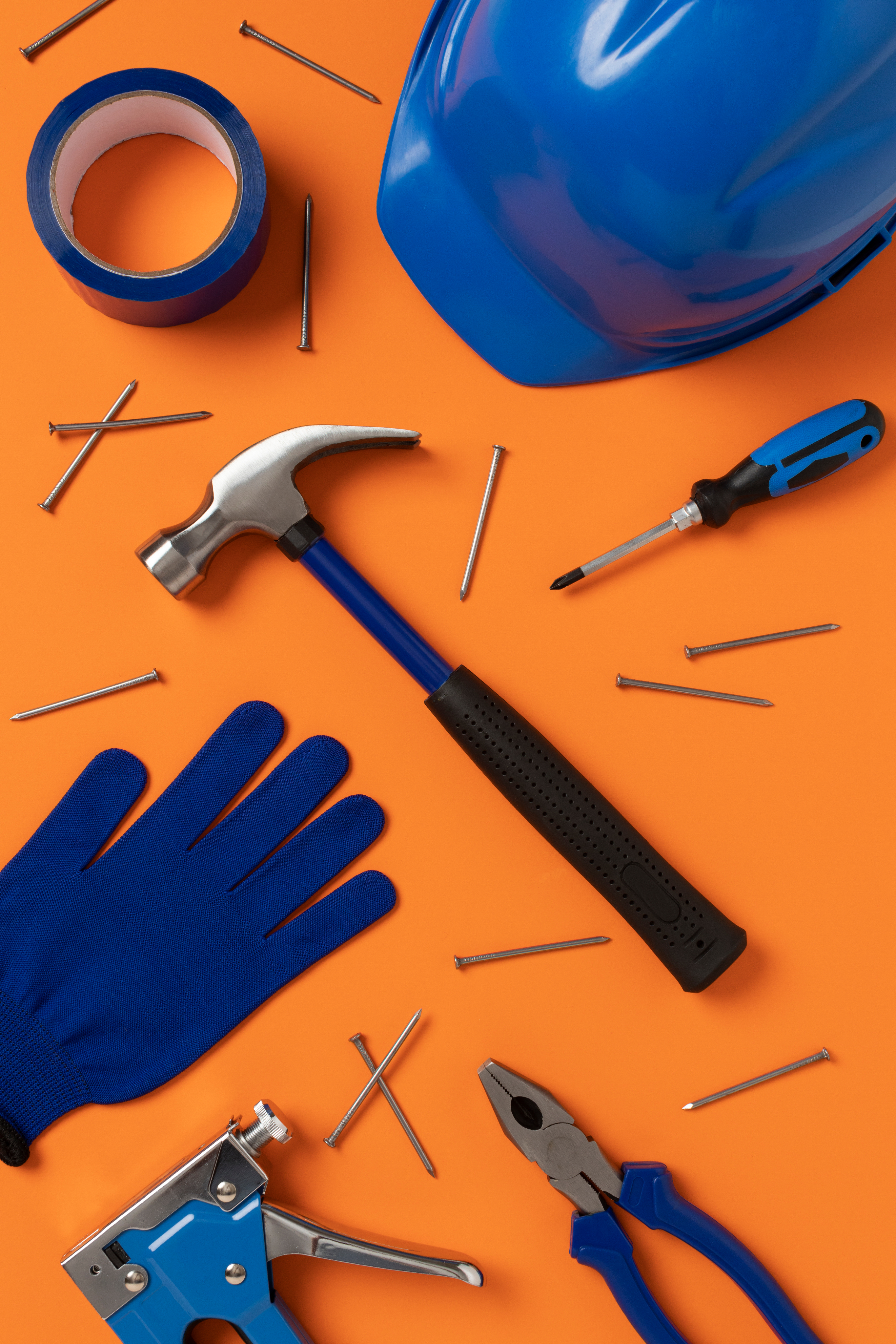 Foto de un martillo con puntillas, guantes, casco y otras herramientas