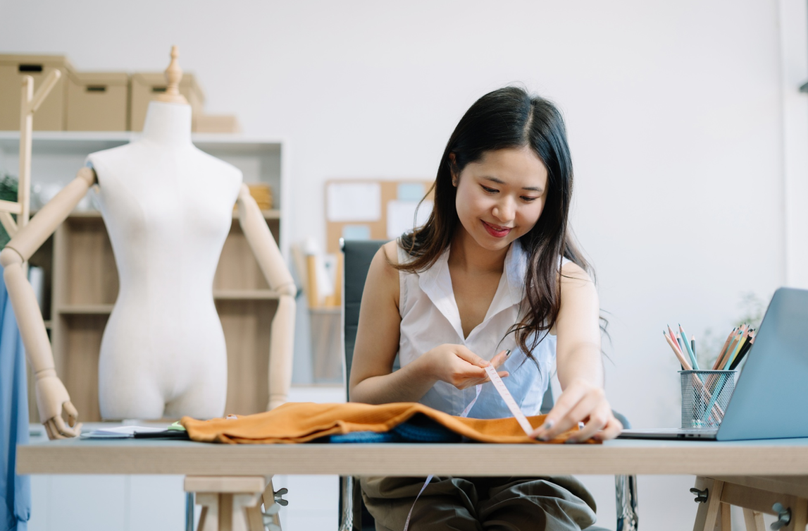 Una mujer tomando medidas con un metro a una prenda de ropa