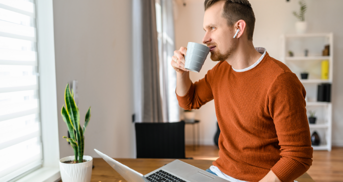 Hombre sonriente que trabaja en la computadora portátil en casa