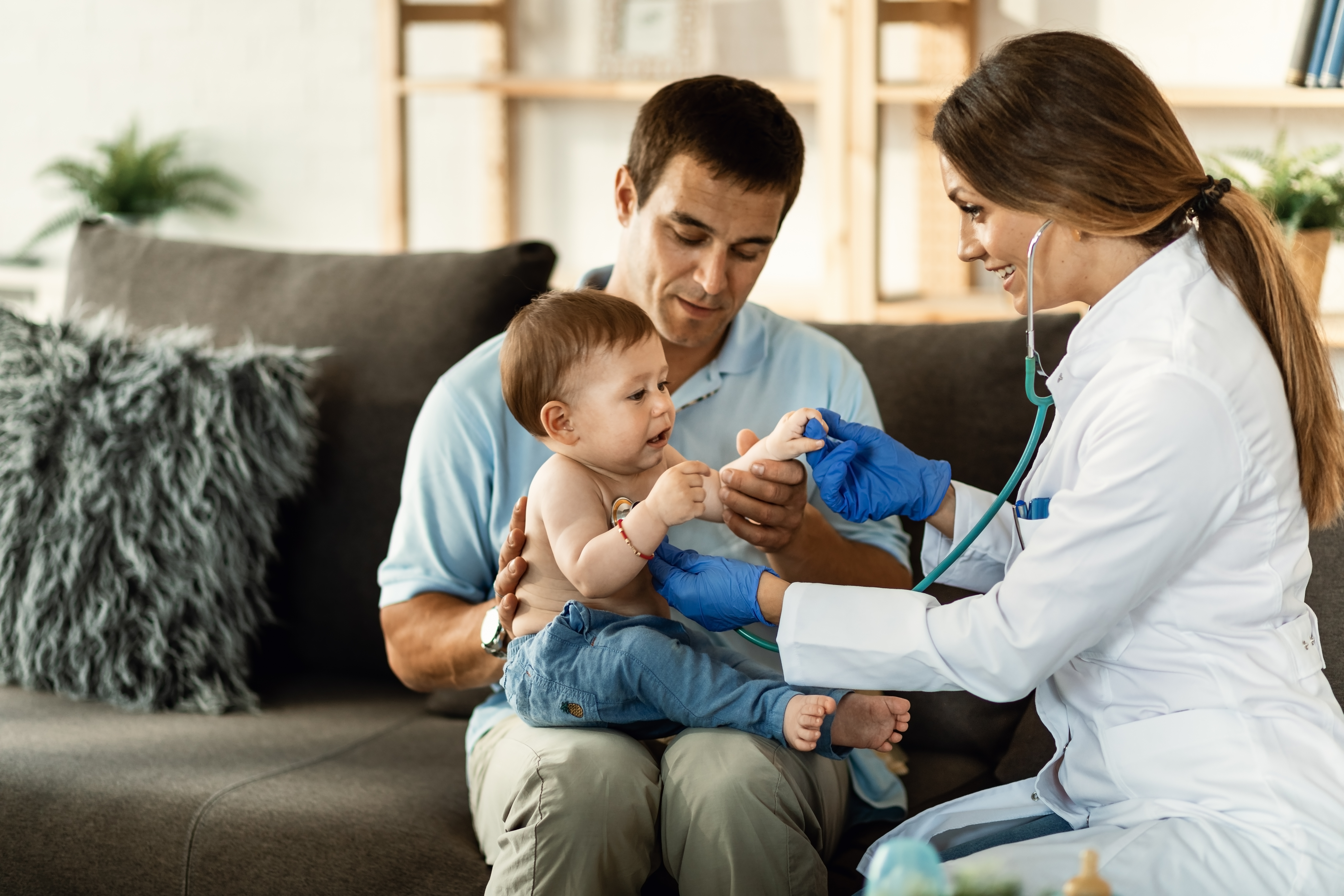 Una doctora feliz escuchando los latidos del corazón de un niño pequeño con un estetoscopio durante una cita médica